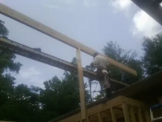Carpenter setting a ridge beam over a new addition frame — Ice Dam Removal by Roofing Brothers in Toston