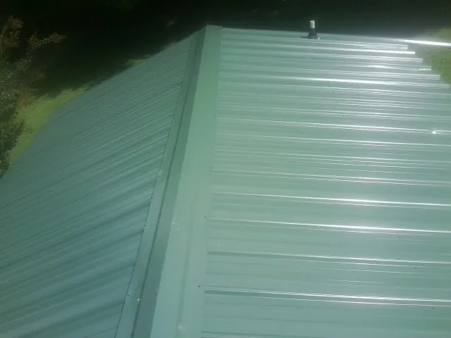 New green metal panels meeting at the ridge of a roof — Flat Roof Repair work by our crew in Toston