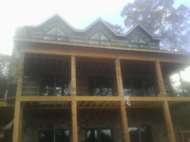 Dormers and porch framing on a large log home under construction — Roof Coating work by our crew in Toston