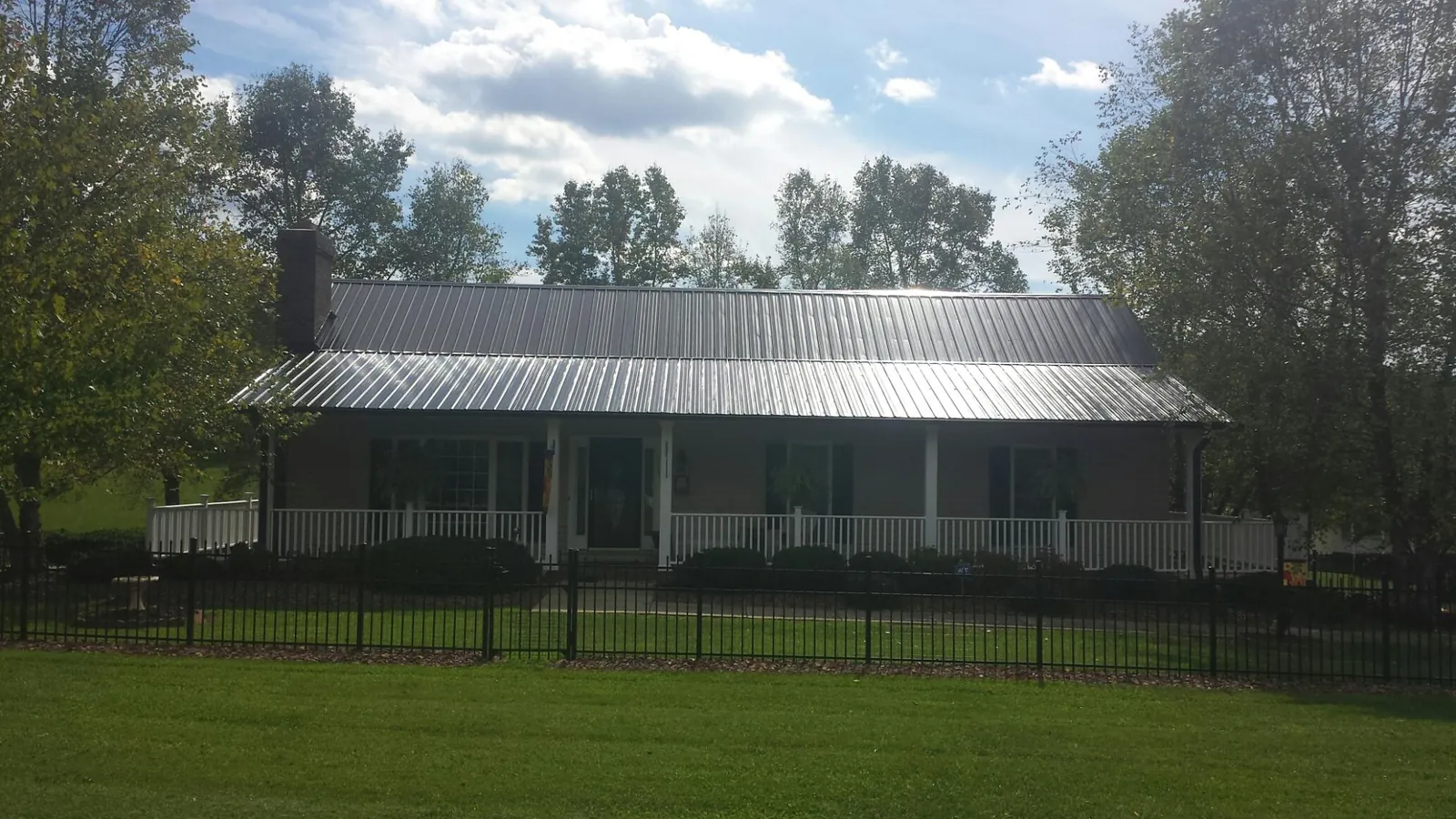 Gray metal roof on a brick ranch with a full width front porch — Gutter Guard Installation work by our crew in Toston