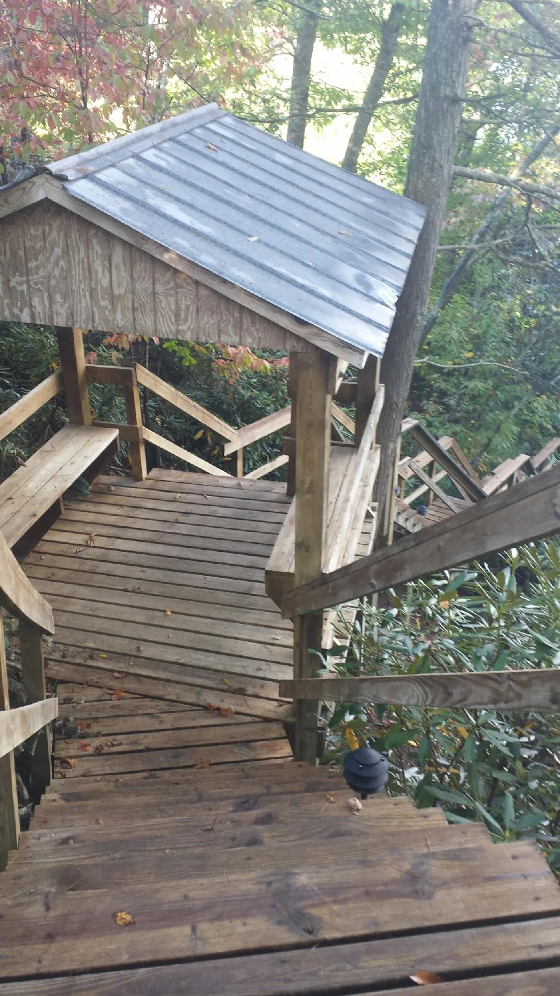 Metal roofed shelter over wooden steps on a wooded walkway — Skylight Repair & Installation work by our crew in Toston