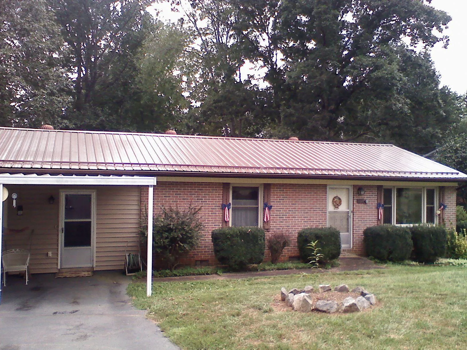 Bronze metal roof and carport on a brick ranch home — Roof Repair work by our crew in Toston