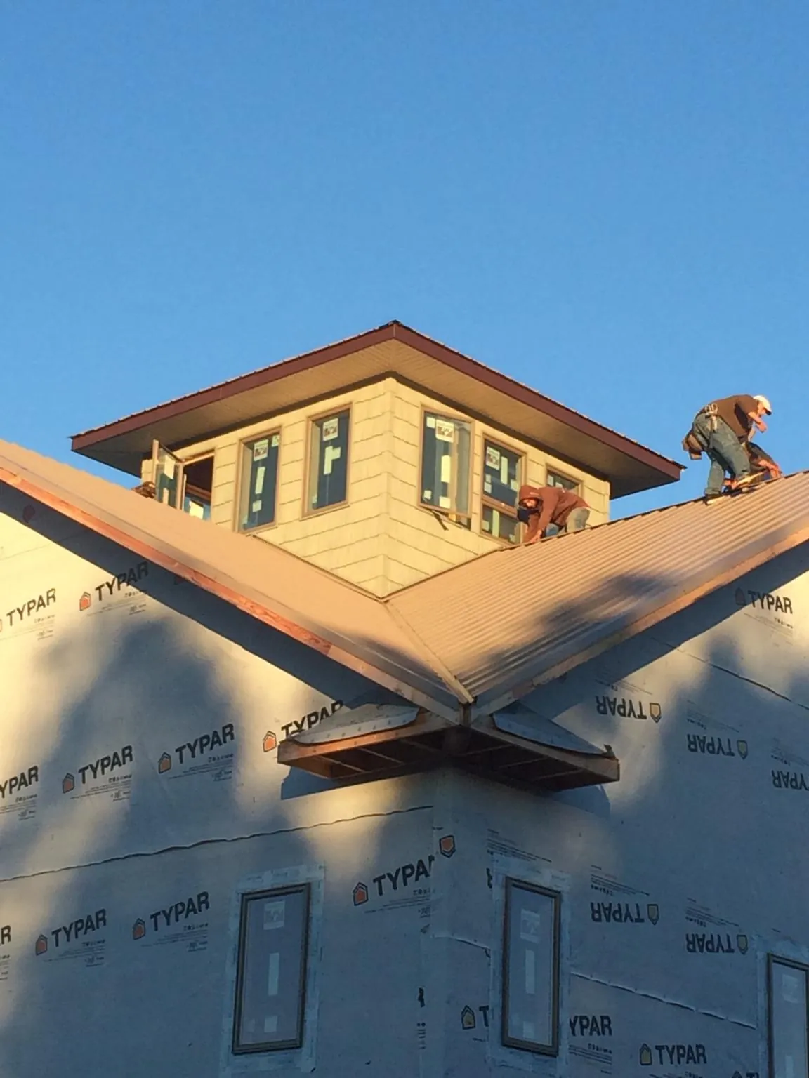 Roofers working around a rooftop cupola on a new metal roof at sunset — Roof Waterproofing in Toston by Roofing Brothers